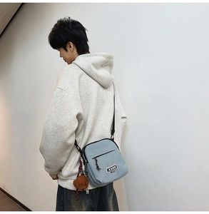 Détail d'un sac bandoulière bleu clair avec sangle réglable et charmant ours en peluche brun