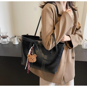 Asian model wearing a black large tote bag with white stitching and bear charm