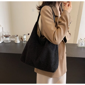 Vue détaillée du sac cabas noir en polaire teddy avec bandoulière sur l'épaule