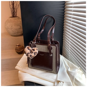Detail of color-block tote bag in brown leather and gray fabric with heart charm