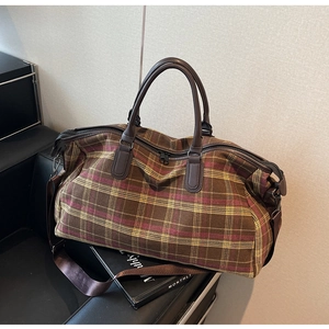 Détail du sac de voyage à carreaux vintage avec poignées en cuir et double fermeture éclair