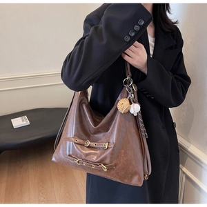 Detail of vintage brown oversized hobo bag in glossy oil wax leather with baseball charm
