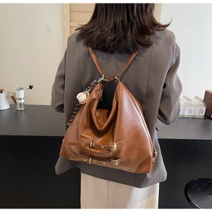 Detail of vintage brown leather backpack with metal buckles and a white baseball charm