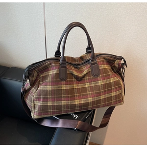 Vue détaillée du sac de voyage à carreaux montrant la texture du tissu et les poignées en similicuir