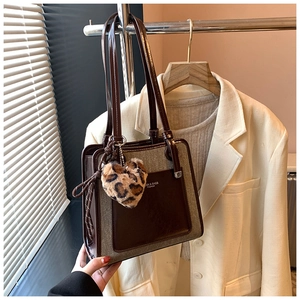 Detail of color-block tote bag with a leopard heart charm and shoulder strap