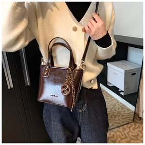 Détail du sac seau en cuir ciré marron foncé brillant avec charm en forme de pretzel