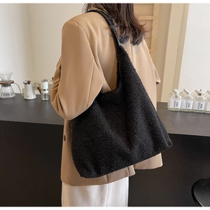 Détail d'un sac cabas en peluche noire avec texture grainée et bandoulière en cuir
