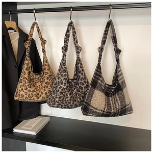 Plush leopard and checkered tote bags with knot handles hanging on a rack display