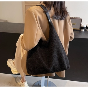 Détail du sac fourre-tout en tissu peluche noir avec texture douce et bandoulière cuir