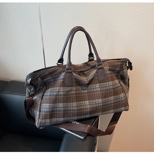 Détail du sac de voyage à carreaux avec poignées en cuir marron et bandoulière réglable