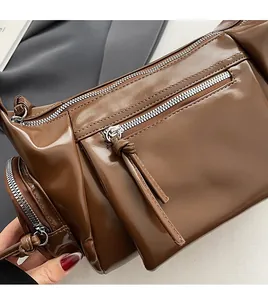 Détail des fermetures éclair en métal argenté sur un sac en cuir marron brillant