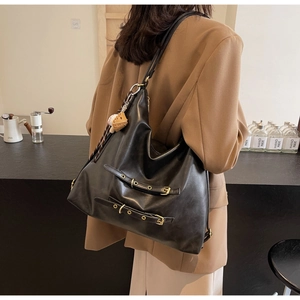 Detail of black large capacity hobo bag with baseball charm and golden buckle accents