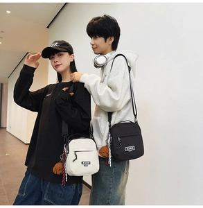 Détail de sacs bandoulière tendance noir et blanc avec pendentif ours en peluche marron