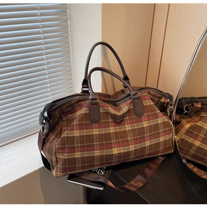 Détail du sac de voyage à carreaux marron avec poignées en cuir et boucles métalliques