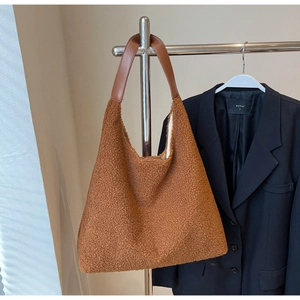 Détail de la texture peluche marron et de la poignée en cuir d'un grand sac cabas
