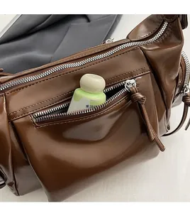 Détail de la poche zippée avant sur un sac bandoulière vintage marron foncé brillant