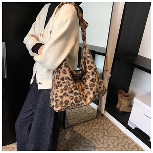 Detail of plush leopard print hobo bag featuring wide knotted shoulder strap and soft faux fur