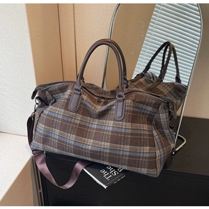 Sac de voyage vintage à carreaux marron avec anses en cuir sur meuble moderne