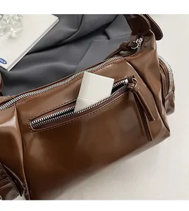 Détail d'un sac porté épaule vintage marron foncé avec poche arrière zippée fonctionnelle