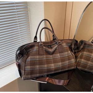 Détail du sac de voyage à carreaux avec poignées en cuir marron et bandoulière large