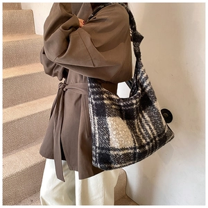 Detail of black and white checkered lamb wool hobo bag worn with a brown autumn coat