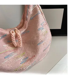 Close-up of pink crescent tote bag with textured embroidery and woven zipper puller