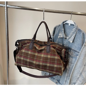 Détail du sac de voyage à carreaux avec poignées en cuir marron et bandoulière réglable