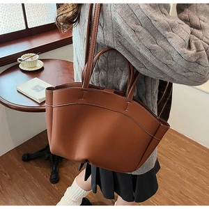 Close-up of brown pebbled leather tote bag with white contrast stitching and soft lining