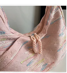 Detail of smooth metal zipper and colorful wavy embroidery on light pink tote bag