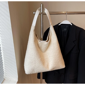 Détail de la texture douce du sac fourre-tout en peluche crème et bandoulière en cuir