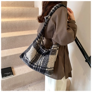 Detail of a large black and white checkered plush hobo bag worn with a winter coat