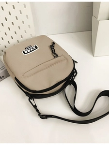 Sac à bandoulière minimaliste en toile kaki avec sangle noire et écusson de la marque