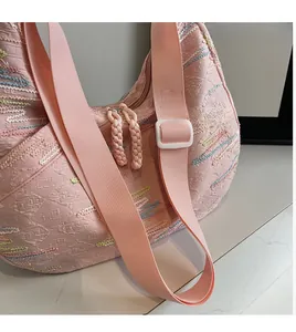 Detail of pink tote bag showing wavy colorful stitching and wide woven shoulder strap