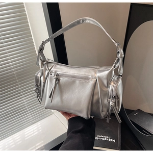 Détail d'un sac argenté métallique avec fermetures éclair décoratives et finition miroir