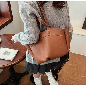 Brown lychee leather tote bag with white contrast stitching detail shown on model
