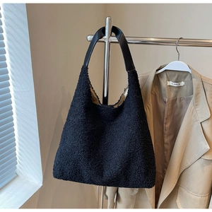 Vue détaillée d'un sac cabas en polaire peluche noire avec des anses en cuir lisse