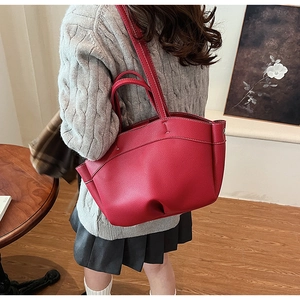 Close-up of red pebbled leather tote bag with white contrast stitching details