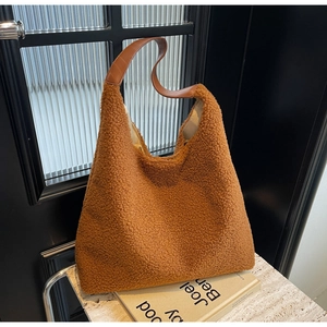 Détail du sac cabas en peluche caramel avec anses en cuir sur socle en marbre