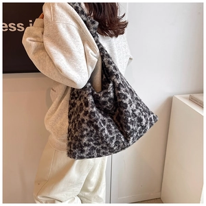 Detailed view of large leopard print plush tote bag worn over the shoulder in casual style