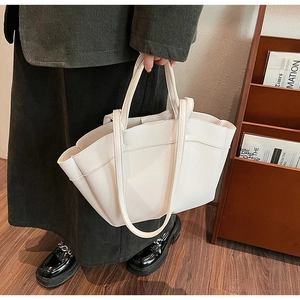 Close-up of a beige lychee pattern leather tote bag with unique side wing structure