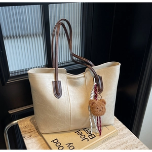 Close-up of beige tote bag texture with brown handles and a cute bear keychain detail