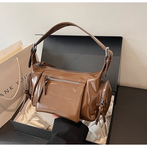 Détail macro d'un sac à main en cuir verni marron avec zips multiples et boucles argentées