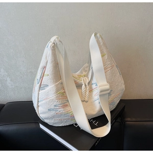 Detail view of white fabric hobo bag with colorful embroidery and textured pattern