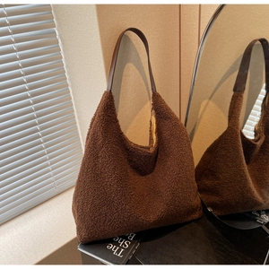 Détail d'un sac cabas en peluche marron doux avec large bandoulière en cuir et lumière chaude