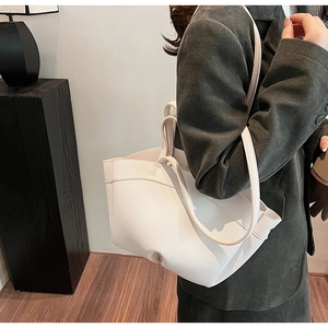 Close-up of a white leather tote bag showing fine lychee texture and slim shoulder straps