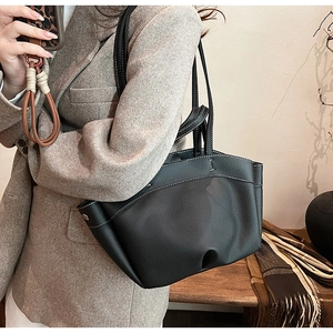 Detail of black pebbled leather tote bag with white contrast stitching on model
