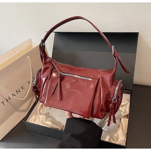 Détail du sac à bandoulière en cuir verni rouge foncé avec fermetures éclair argentées
