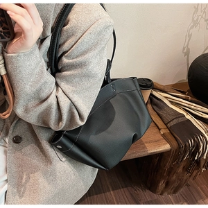 Detail of black pebbled leather tote with contrast white stitching and metal I-shaped logo