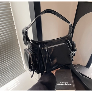 Détail du sac à bandoulière noir brillant avec poches multiples et zips à franges