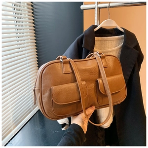 Detail of vintage brown shoulder bag showing PU leather texture and front flap pockets